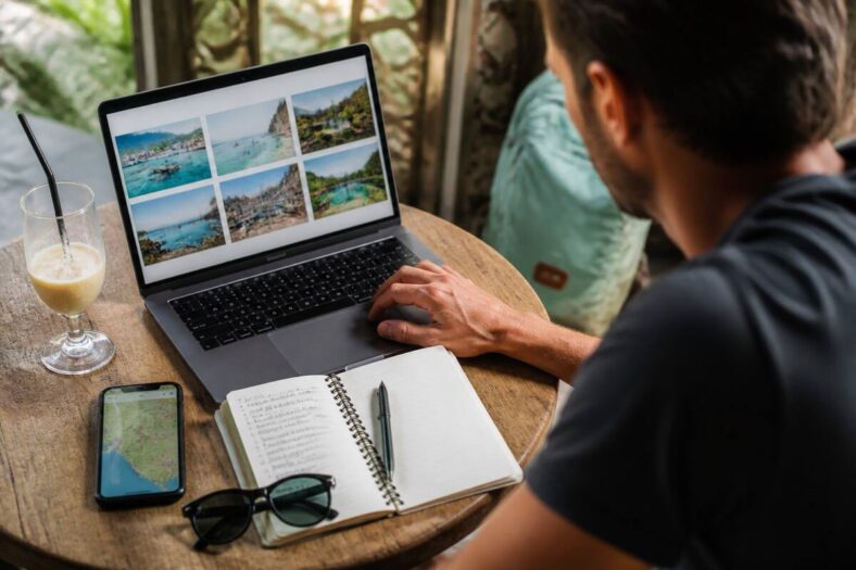 Reiziger vergelijkt vakanties op laptop en smartphone in een café