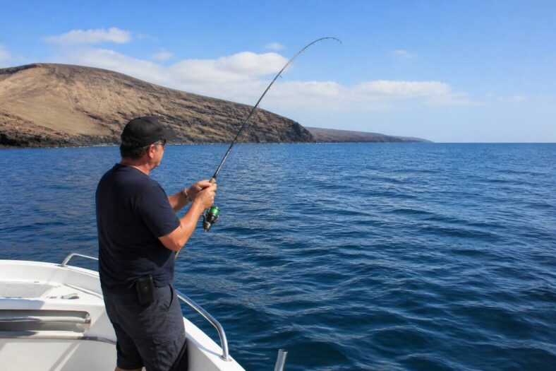 Sportvisser aan het vissen vanaf een boot langs de rotsige kust van Lanzarote